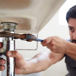 Plumber fixing bathroom sink pipe