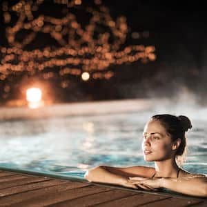 Young woman relaxing in heated swimming pool during winter night