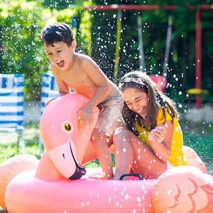 Two kids in bathing suits playing with pool noodles and squirt guns