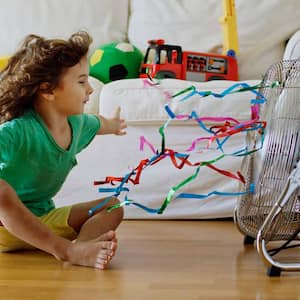 A kid in front of a fan