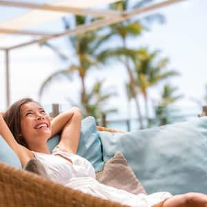 Women lounging in outdoor rattan chair with blue pillows