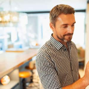 A man adjusting the temperature on a digital thermostat