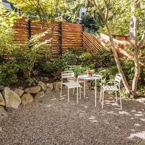 A backyard with a stained wood fence, table, and chairs