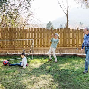 Grandparents playing soccer with grandkids in the yard