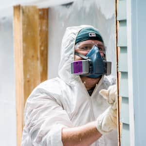 contractor in haz-mat suit scraping paint from home exterior