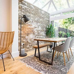 A living room with a brick wall and an extension with a glass conservatory room