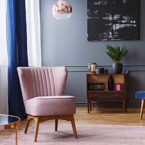 A pink armchair in a living room with dark gray walls