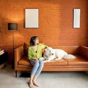 Woman and dog sitting on a leather couch
