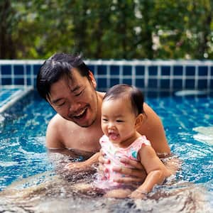 father embracing daughter while swimming in swimming pool