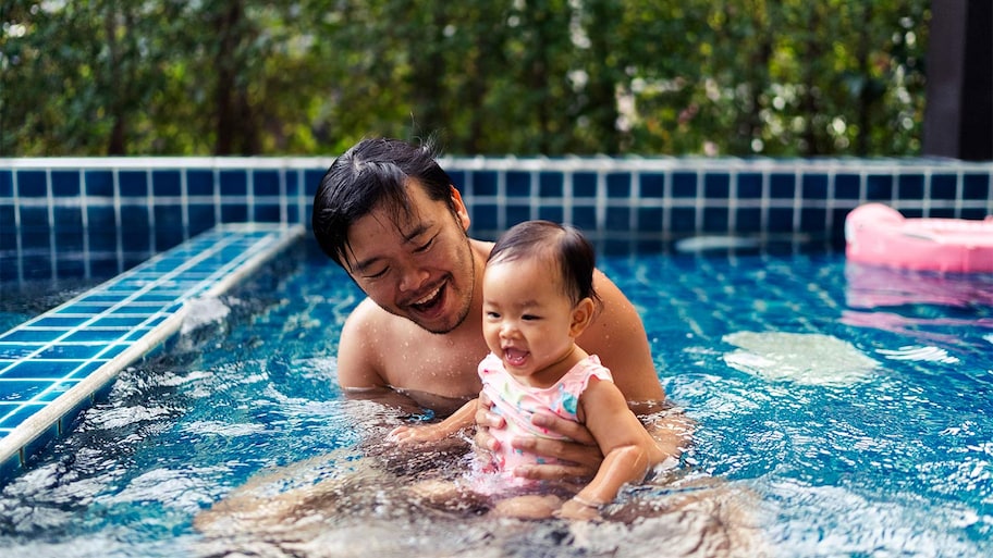 father embracing daughter while swimming in swimming pool