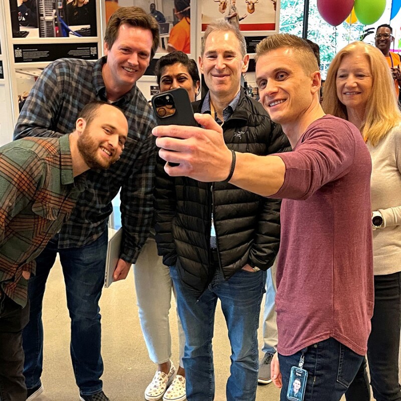 A photo of CEO Andy Jassy standing with three employees, taking a photo together at Amazon’s Seattle headquarters.