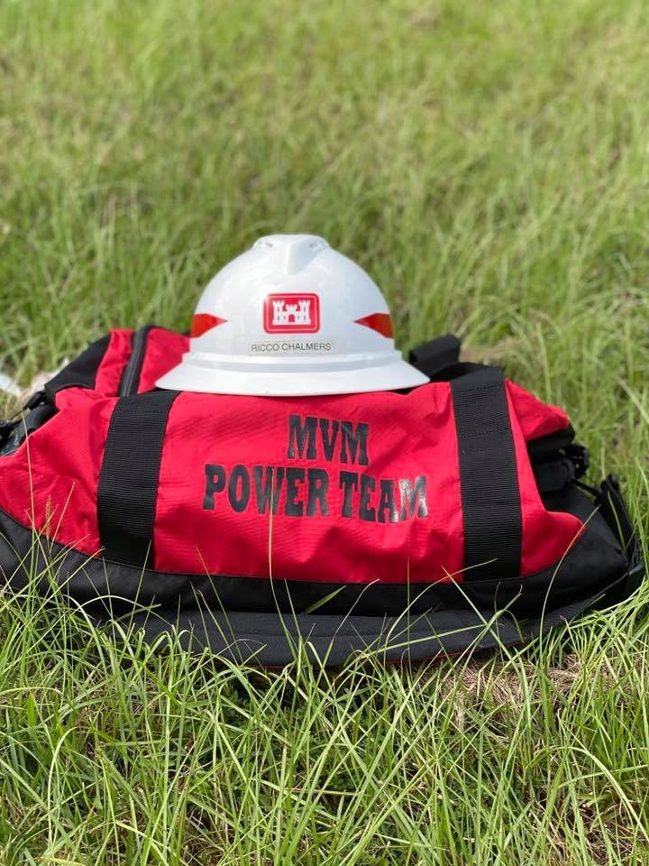 Photo shows duffle bag and hard hat on ground.