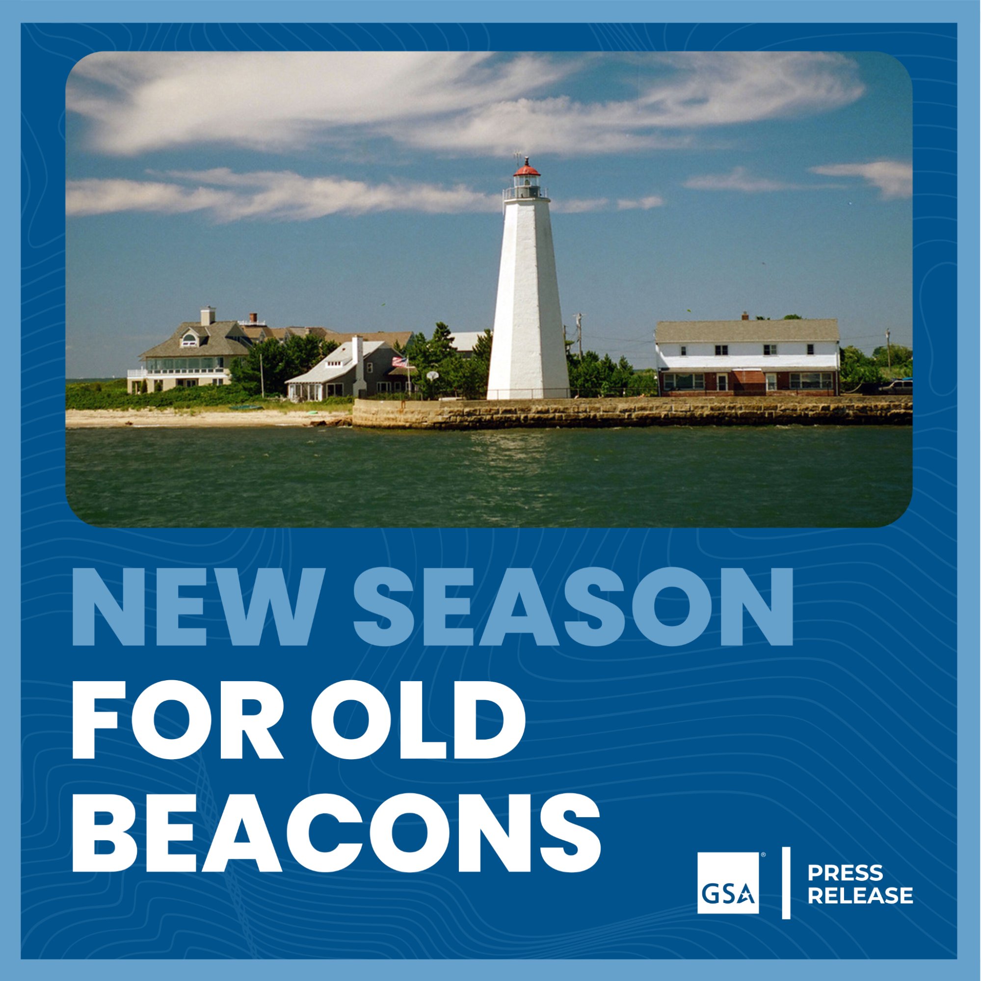 White lighthouse with two smaller houses next to it on either side. There is a beautiful green lake in the foreground and the text on the blue border of the picture says, "New Season for Old Beacons"