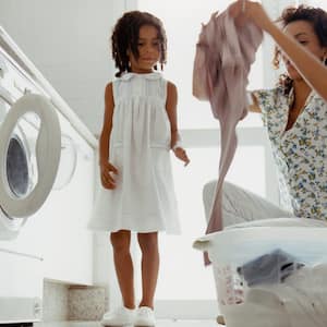 Girl watcher her mom doing laundry