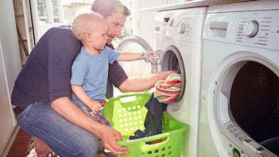 Father and toddler son doing laundry at home