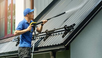 man pressure washing roof