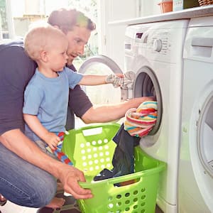 Father and toddler son doing laundry at home