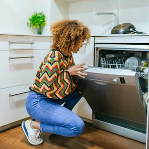 Woman in her apartment loading dishwashe