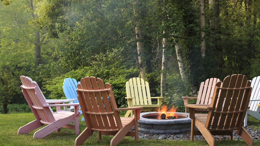 Adirondack chairs painted different colors around fire pit