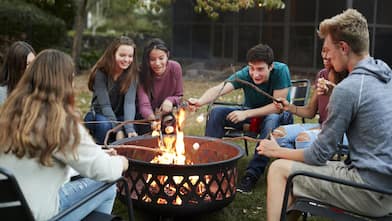 Friends sit around a fire pit