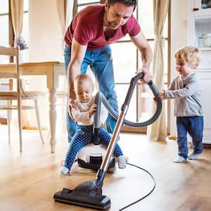 Father vacuuming with children