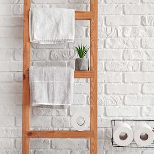 Wooden towel ladder against a brick wall