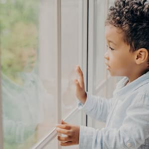 Little boy looking out a big window