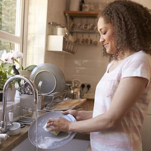 Woman washing dishes at farmhouse sink