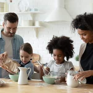 Family of four mixes ingredients atop a butcher block countertop island