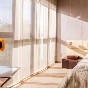 A sunlit bedroom with a sunflower in a vase