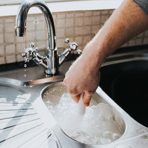 Man fixing kitchen sink clog 