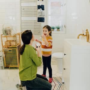 A girl and her mother applying moisturizer in the bathroom 