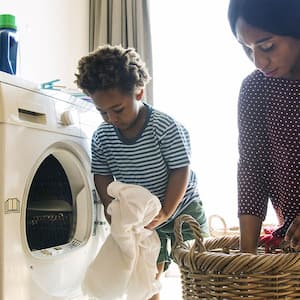 Mother and son take laundry from dryer into basket