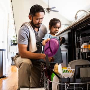 A father and his daughter loading the dishwasher