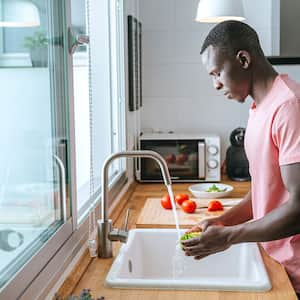 Man washing lettuce in kitchen sink