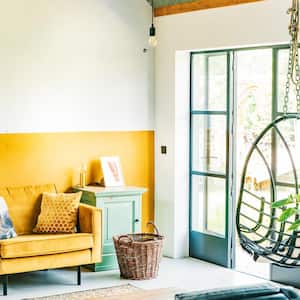 A bright boho interior with a mustard wall matching an armchair