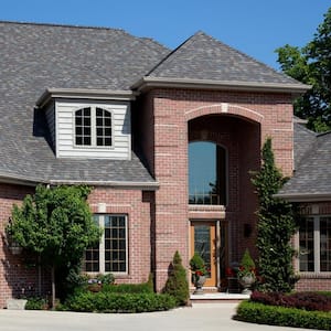 The exterior of an exposed brick house with dark shingles