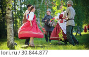 Two couples in Russian clothes dancing traditional dances on the field by the accordion music. Стоковое видео, видеограф Константин Шишкин / Фотобанк Лори