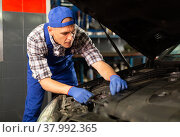 Car mechanic looking at open car hood for internal checking. Стоковое фото, фотограф Яков Филимонов / Фотобанк Лори