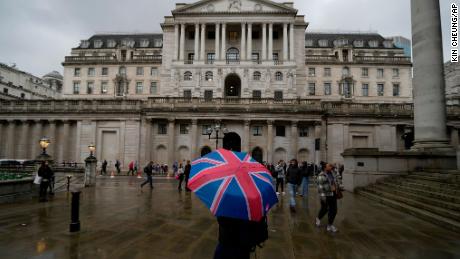 A woman with an umbrella stands in front of the Bank of England, at the financial district in London in this November 3, 2022 file photo.