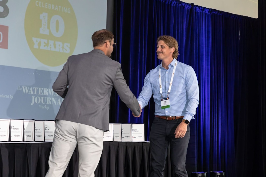 Two men shake hands on stage as an award is presented. 