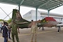 Three men speak near a military plane