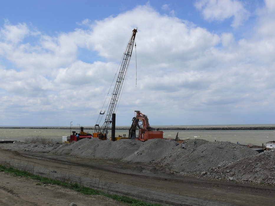 Ryba Marine Construction pump equipment sits along the Dike 12 wall with the Cleveland Breakwater in the background.

