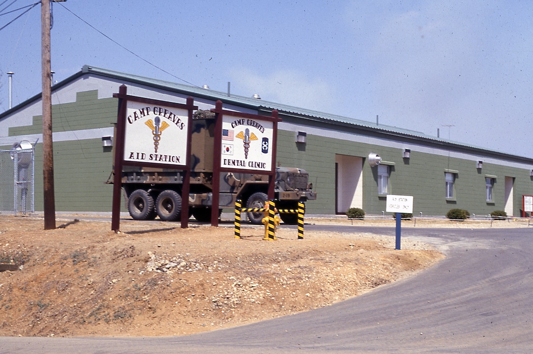 Large green building with two signs in front.