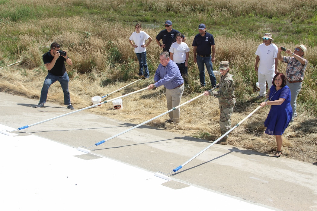 Col. Julie Balten, the second from right with a paint roller in hand, U.S. Army Corps of Engineers Los Angeles District commander, joins U.S. Rep. Ken Calvert (CA-42), center of frame and foreground, and Riverside County Second District Supervisor Karen Spiegel, right, to add the ceremonial finishing touches June 2 to the newly restored bicentennial mural on the Prado Dam spillway in Corona, California.