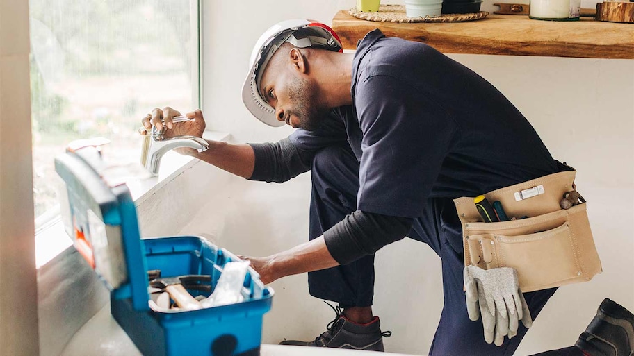 professional man fixing leaky faucet with tool box