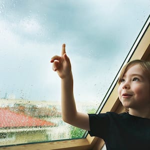 Child watching the rain from a rooftop window