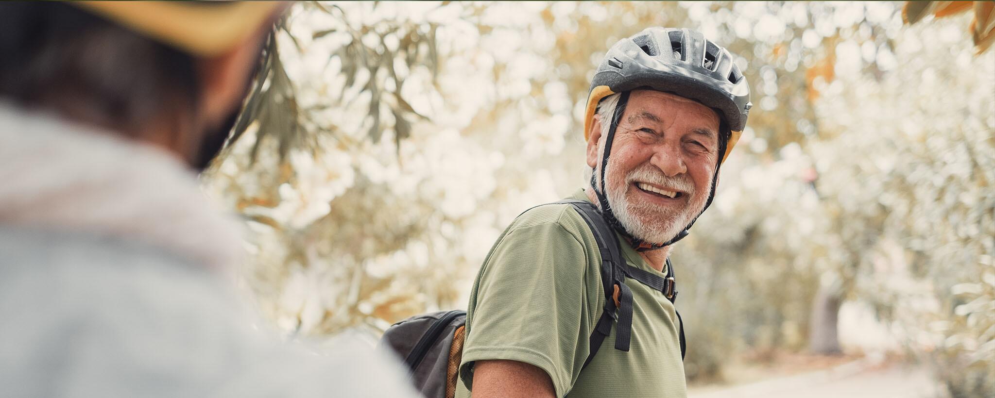 Older man wearing a helmet on a bike. 