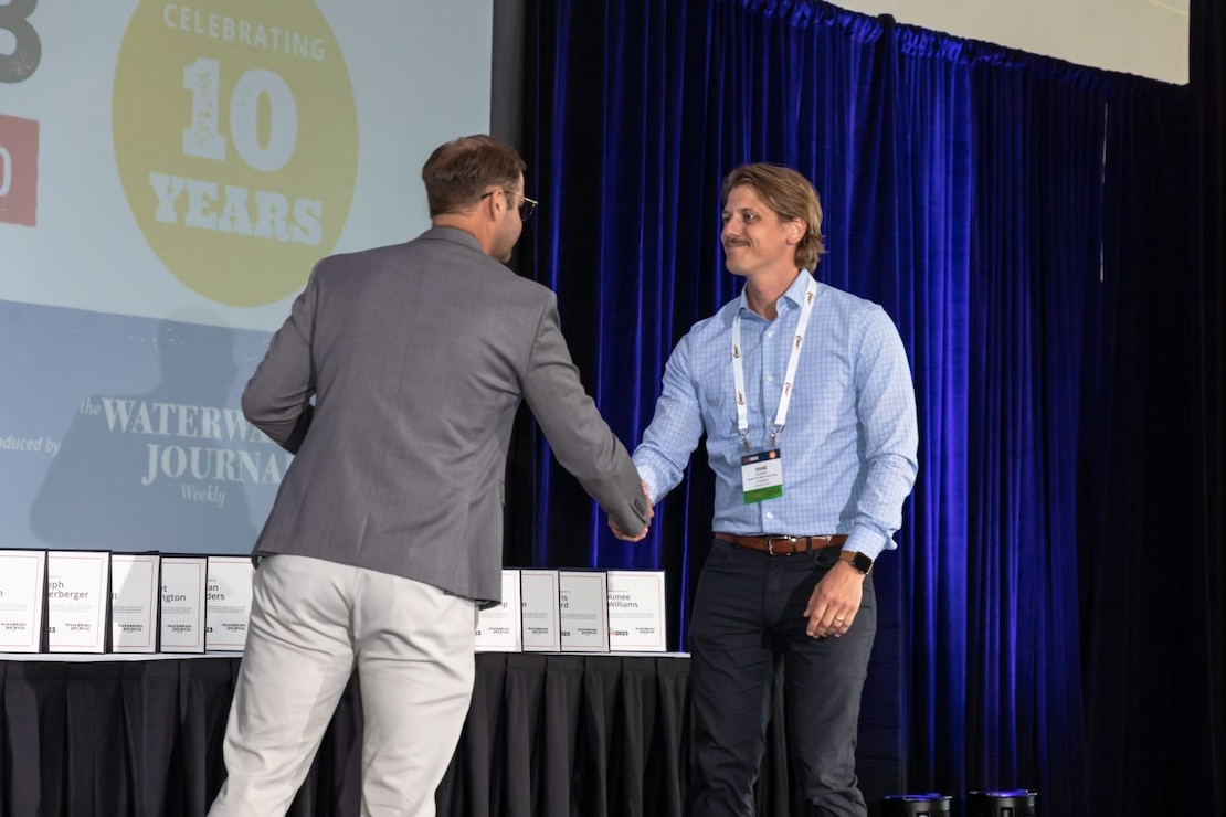 Two men are on a stage shaking hands as an award is presented.