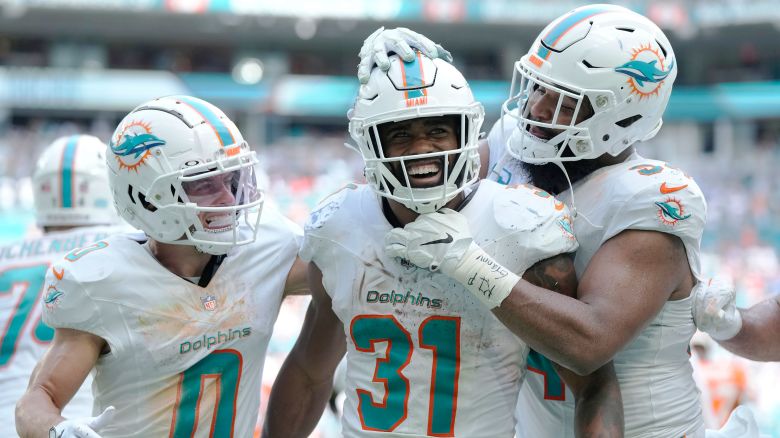 Miami Dolphins running back Raheem Mostert (31) is congratulated by wide receiver Braxton Berrios (0) and defensive tackle Christian Wilkins (94) after scoring a touchdown during the second half of an NFL football game against the Denver Broncos, Sunday, Sept. 24, 2023, in Miami Gardens, Fla. (AP Photo/Rebecca Blackwell)